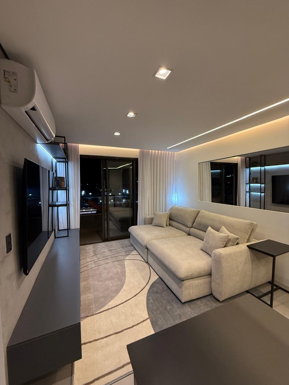 Sala de estar mobiliada do apartamento 704 com vista noturna de Belo Horizonte